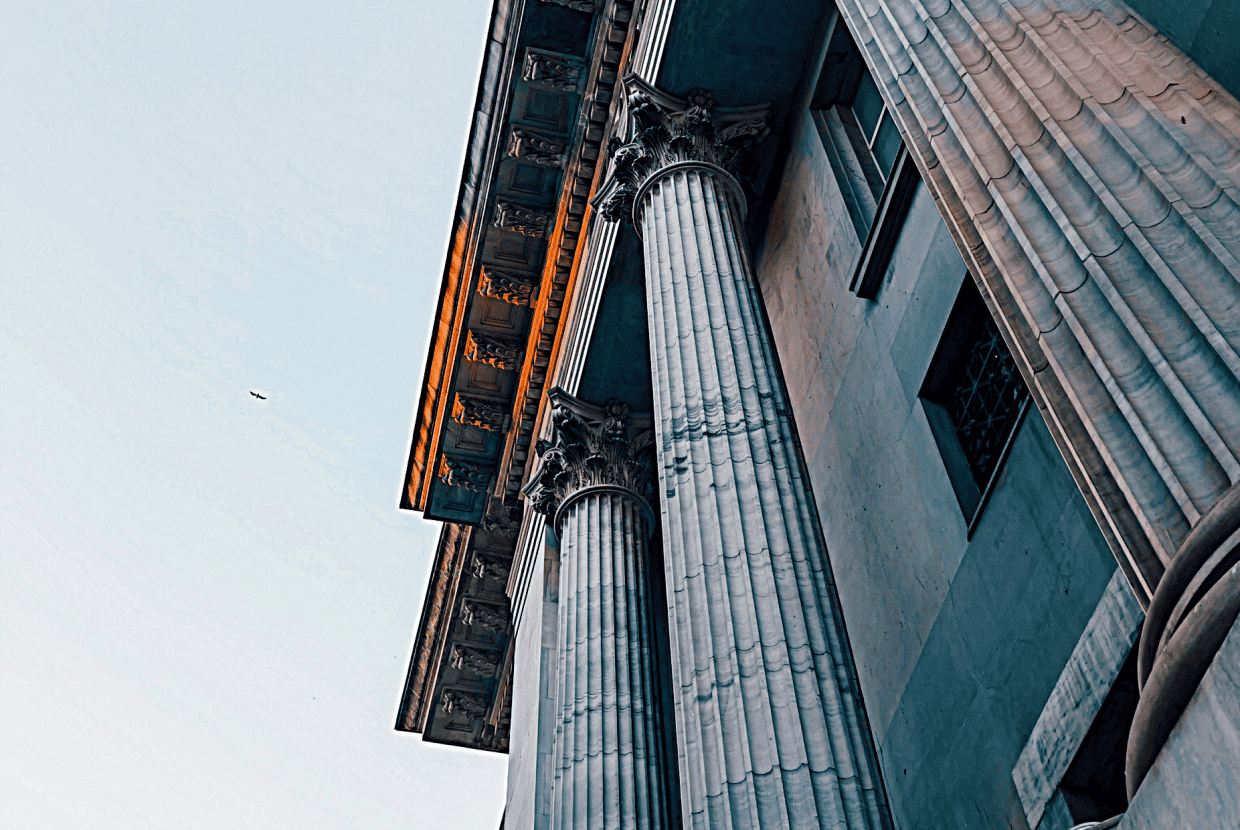 Upward view of tall stone columns and ornate classical architecture on a historic building.
