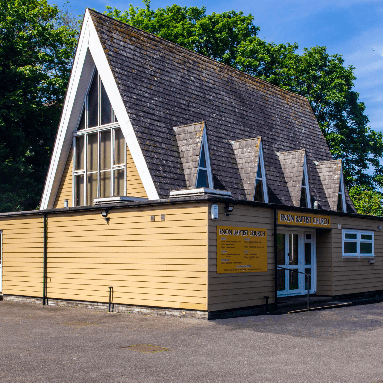 Exterior of Enon Baptist Church building with pitched roof and large front windows.