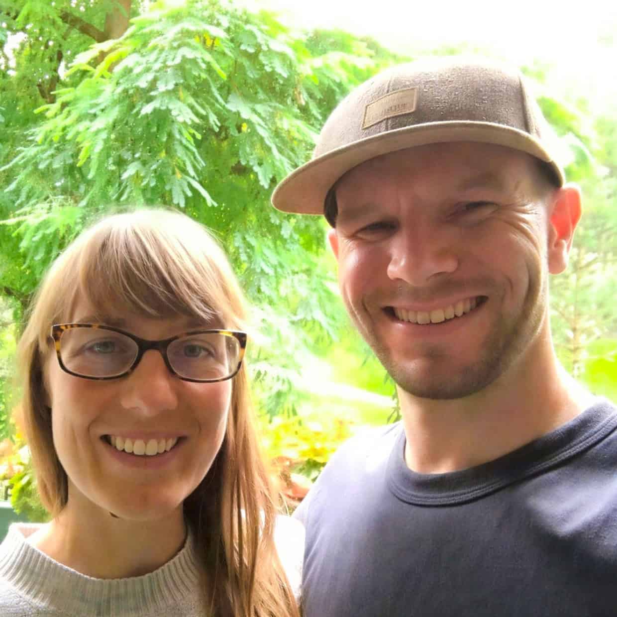 Steve and Tanya Bownds smiling together outdoors with trees and greenery in the background.